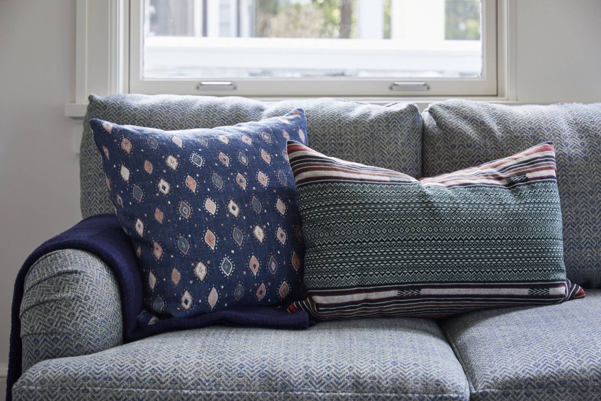 Blue herringbone sofa with patterned throw pillows